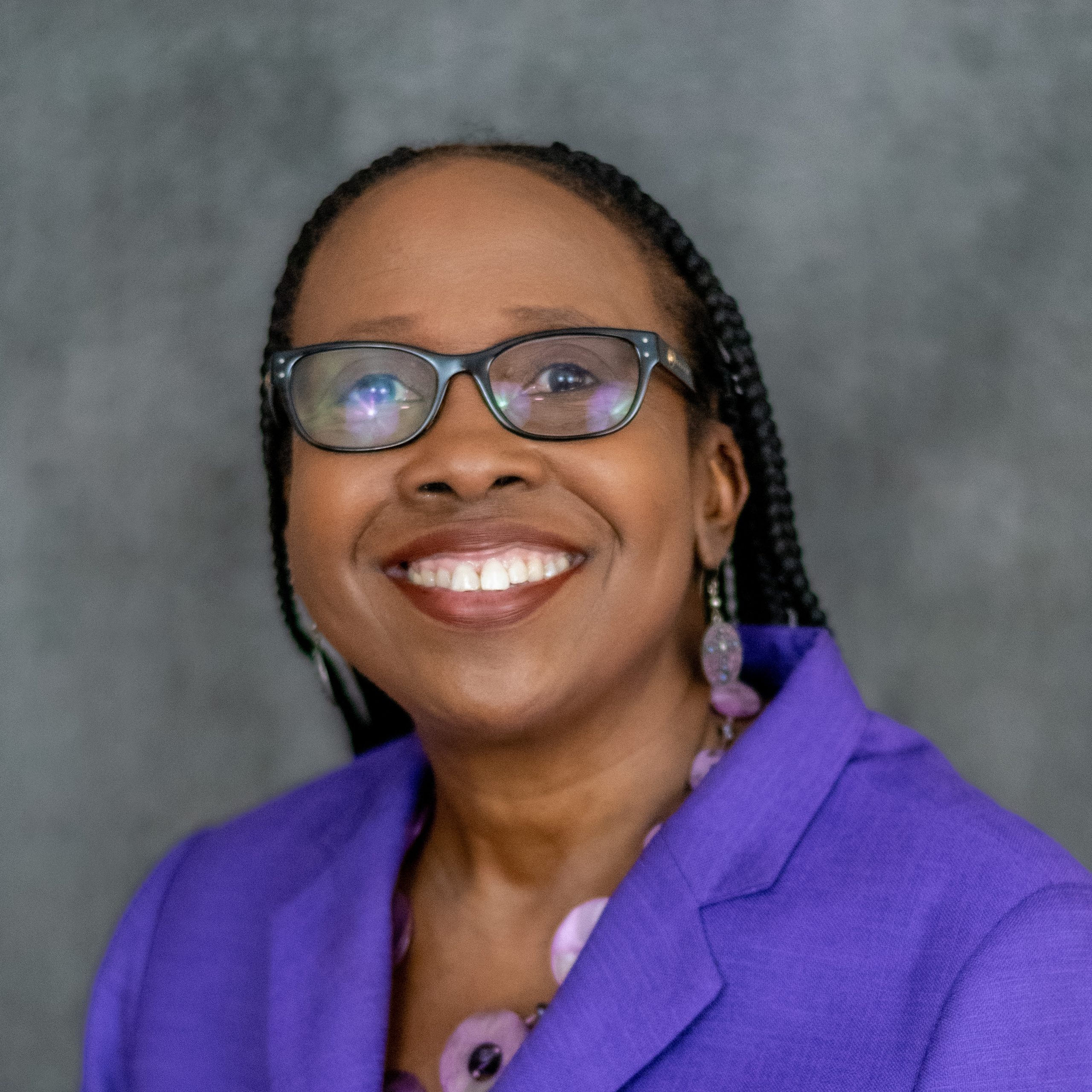 DeLaine Priest is a black woman wearing glasses and a purple suit